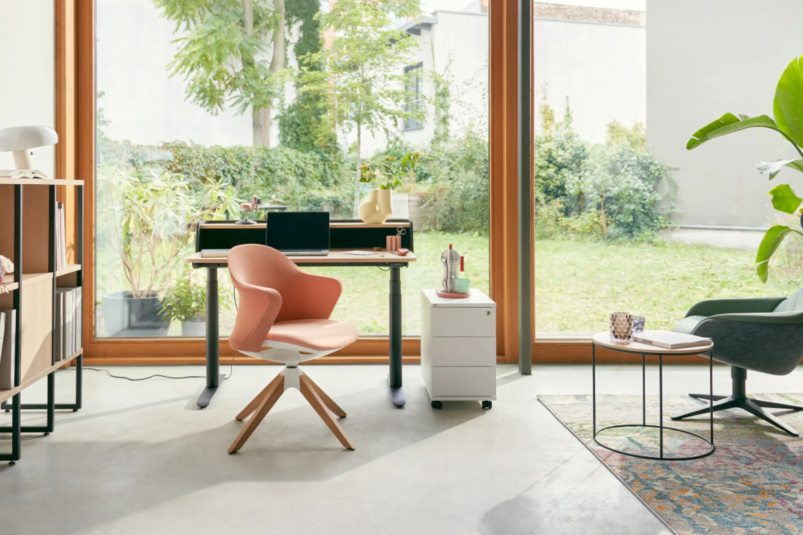 Wohnliche Arbeitsecke mit sedus se:flair Stuhl, Schreibtisch und Rollcontainer vor Glasfront