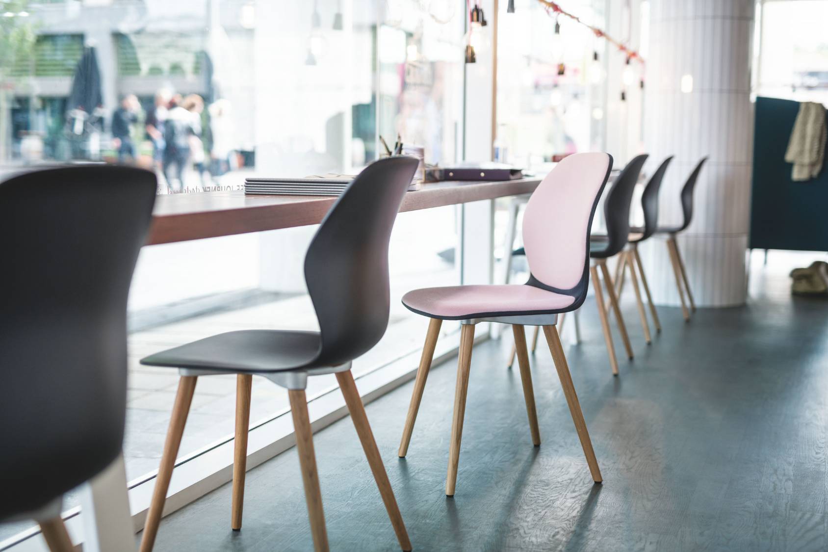 se:spot Stühle mit schwarzer und rosa Sitzfläche, Holzbeinen, modernes schlankes Design an einer Fensterbar in hellem Raum