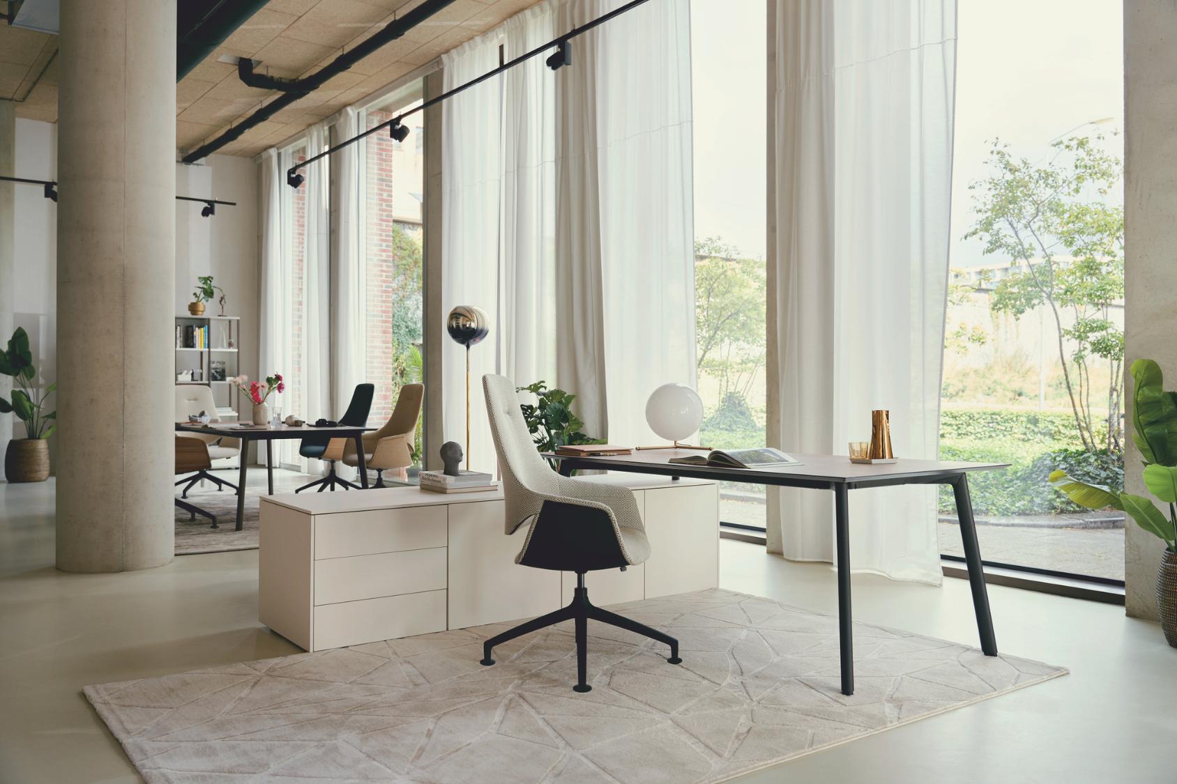 Der se:mission Bürostuhl in Weiß mit schwarzem Fußkreuz steht an einem modernen Schreibtisch vor bodentiefen Fenstern in einem hellen Büro mit minimalistischer Einrichtung.