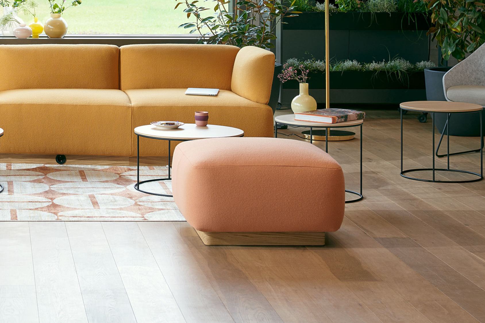 se:living Hocker mit rechteckigem, abgerundetem Design in Rosa, gepolstert auf Holzsockel, vor gelbem Sofa und runden Beistelltischen