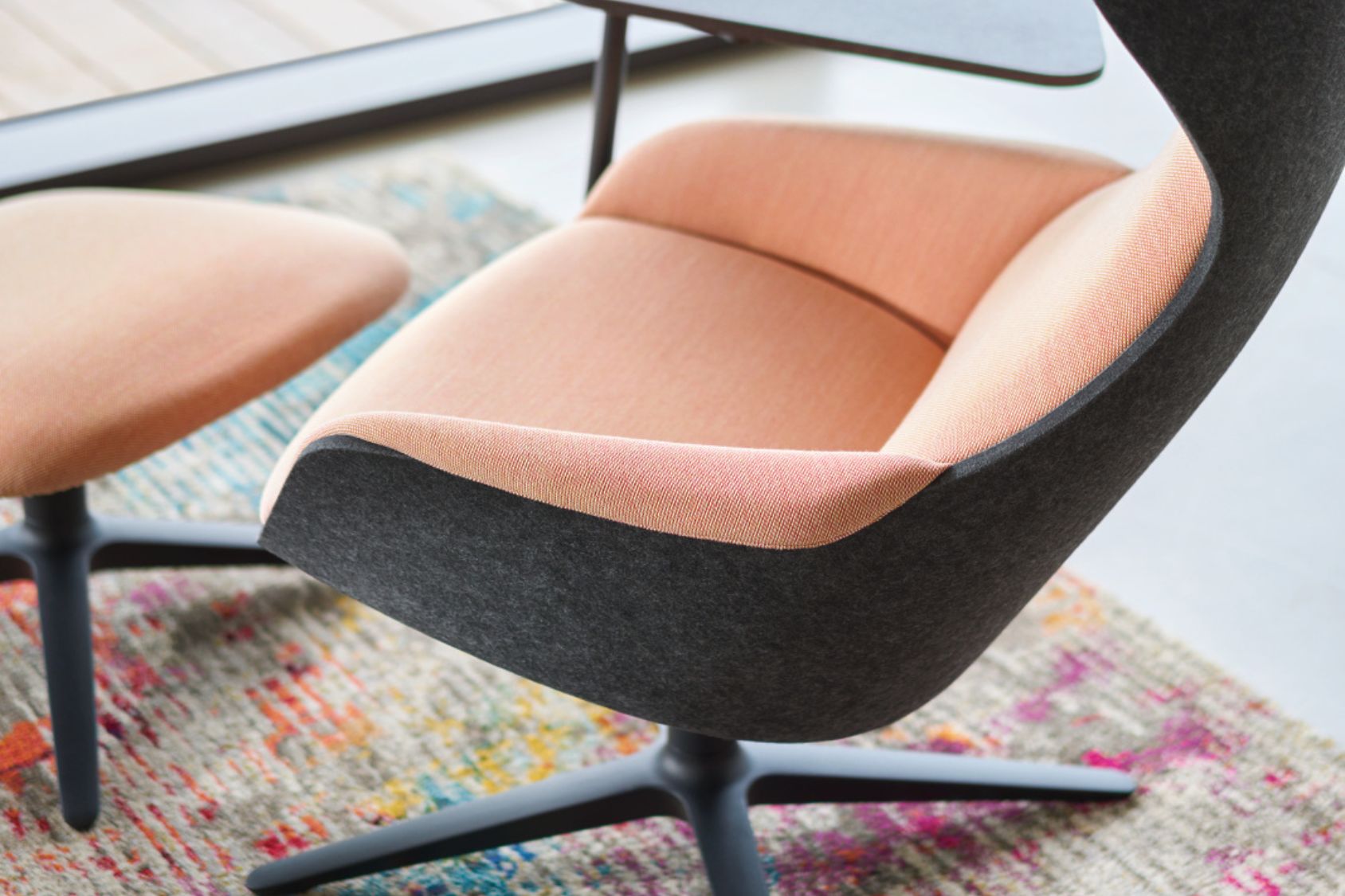 se:lounge Sessel mit abgerundetem Design, schwarzer Außenhülle und rosafarbenem Innenpolster auf buntem Teppich