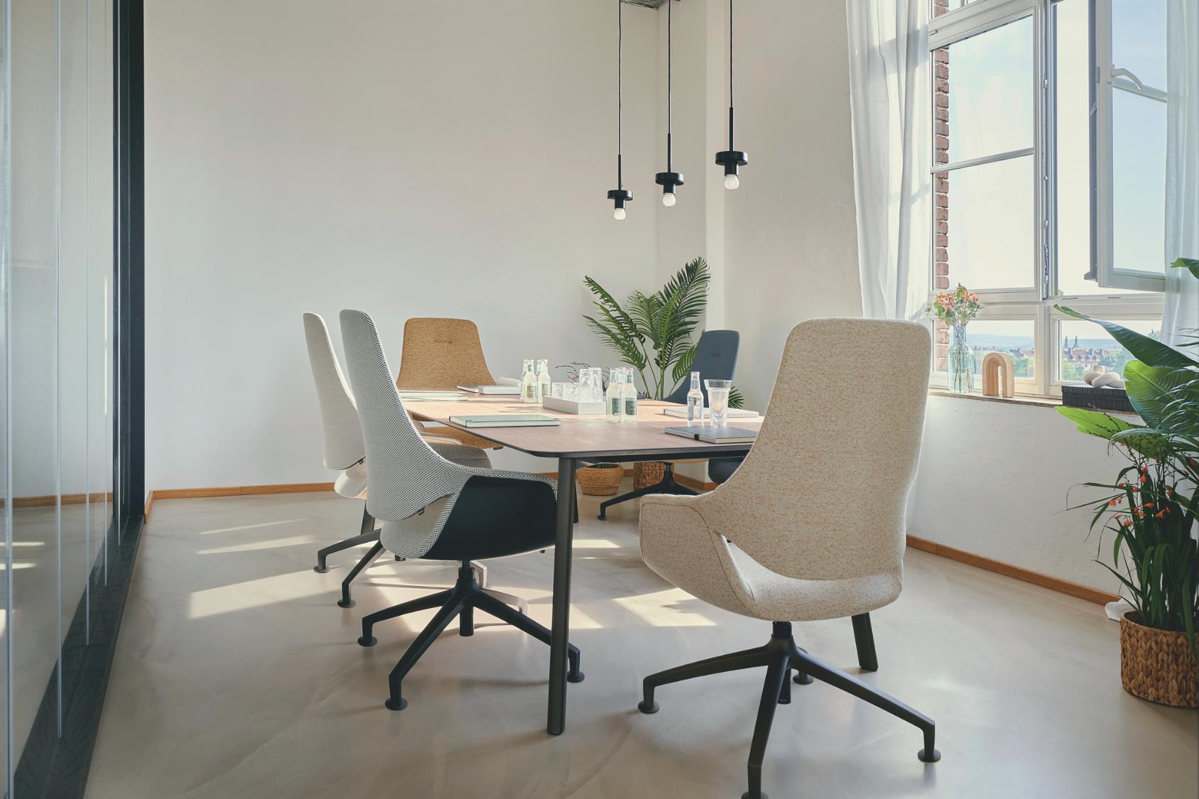se:mission Stuhl in beige, ergonomisch geformt mit schwarzem Drehfuß, an einem Konferenztisch in hellem Raum mit großen Fenstern