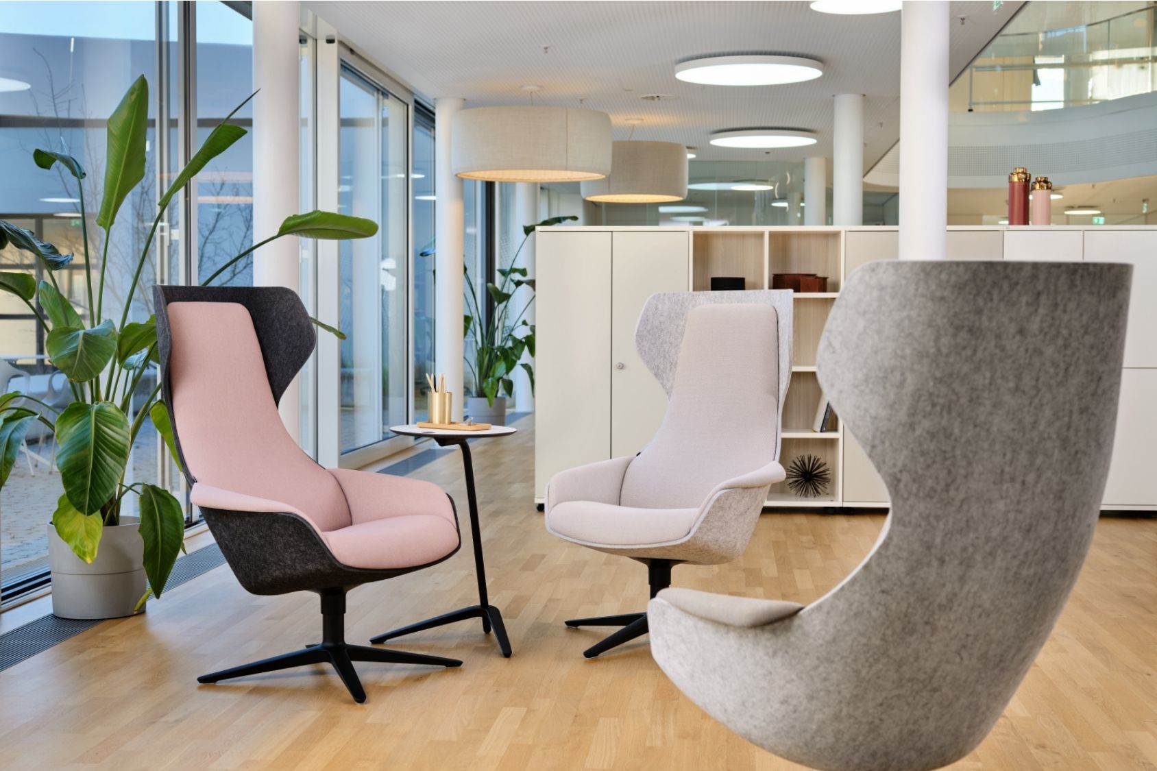 Drei se:lounge Sessel mit modernem, ergonomischem Design und hoher Rückenlehne in einem hellen Büro mit Holzboden und großen Fenstern
